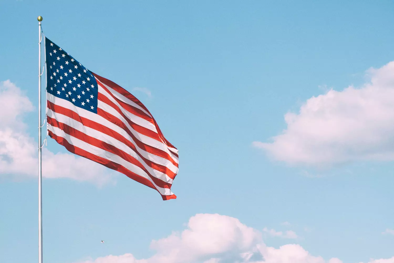 Флаг США на фоне чистого неба, воплощающий суть Америки Развивающийся флаг США на фоне ясного неба, символизирующий американский дух и культуру