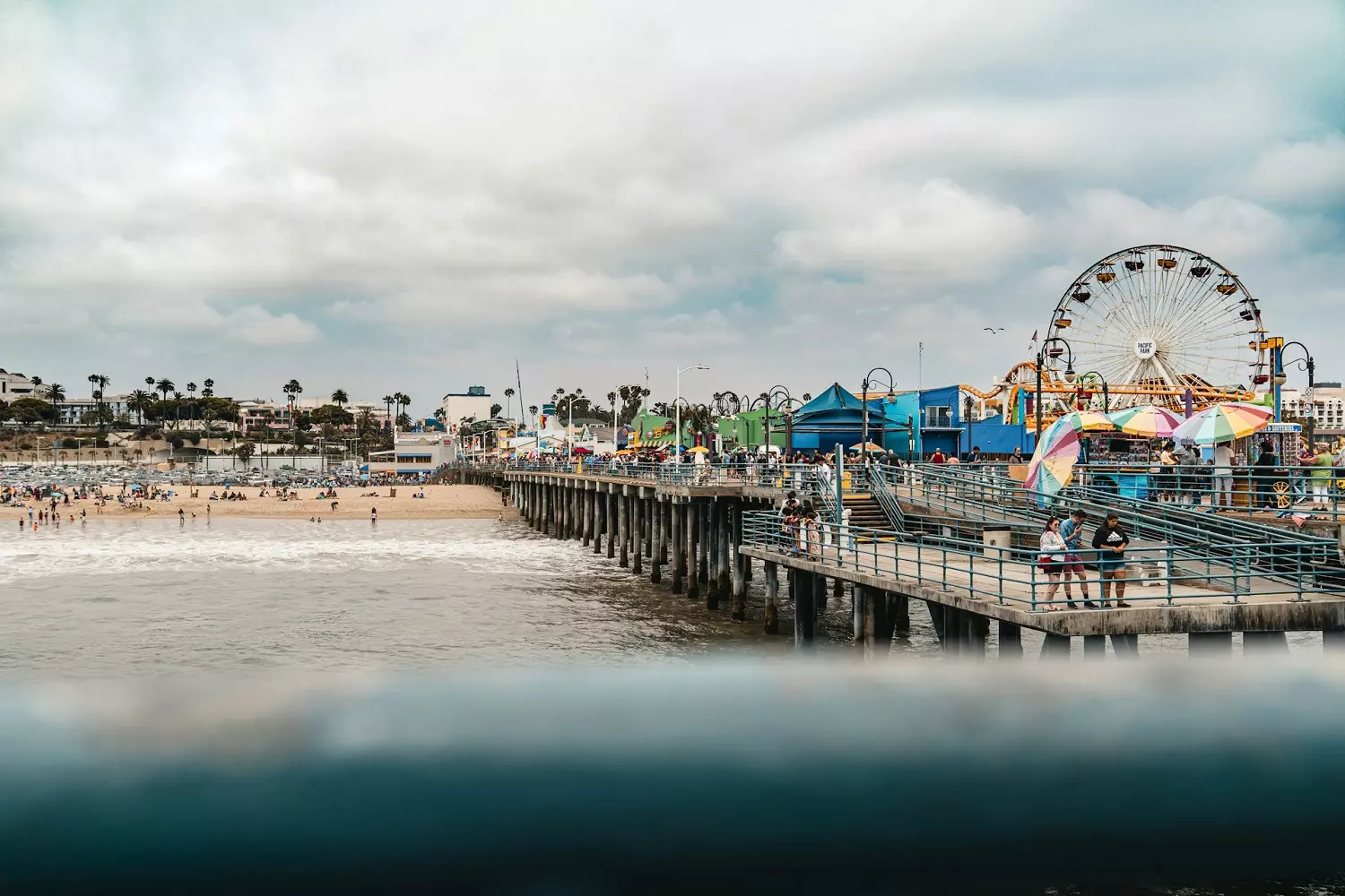View of Santa Monica Pier from the ocean A bustling Santa Monica Pier with rides under a cloudy sky