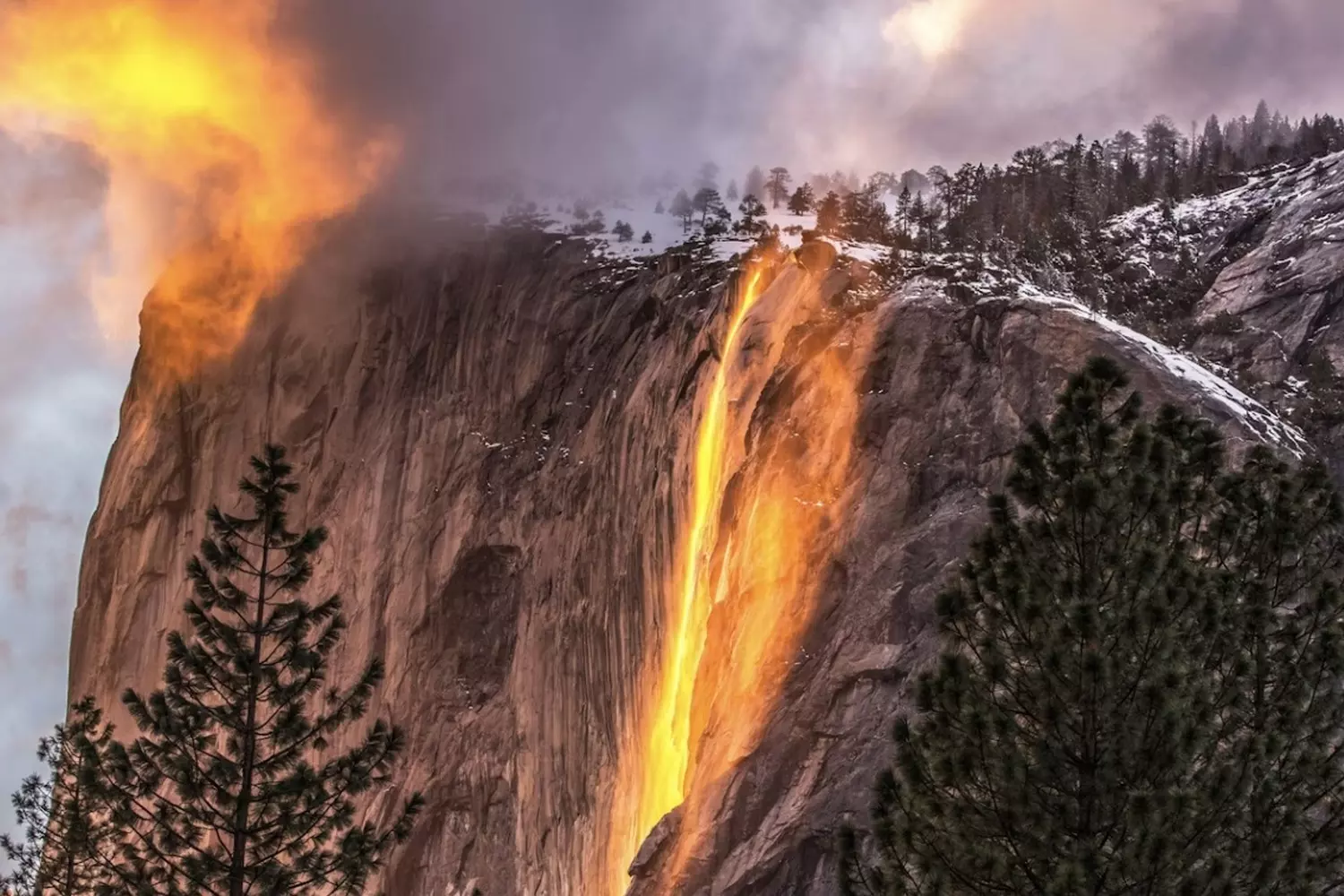 Liquid Fire: Yosemite Waterfall Bathed in Sunset Glow Golden sunset over Yosemite's cascading waterfall with warm hues reflecting on the mist and surrounding granite cliffs