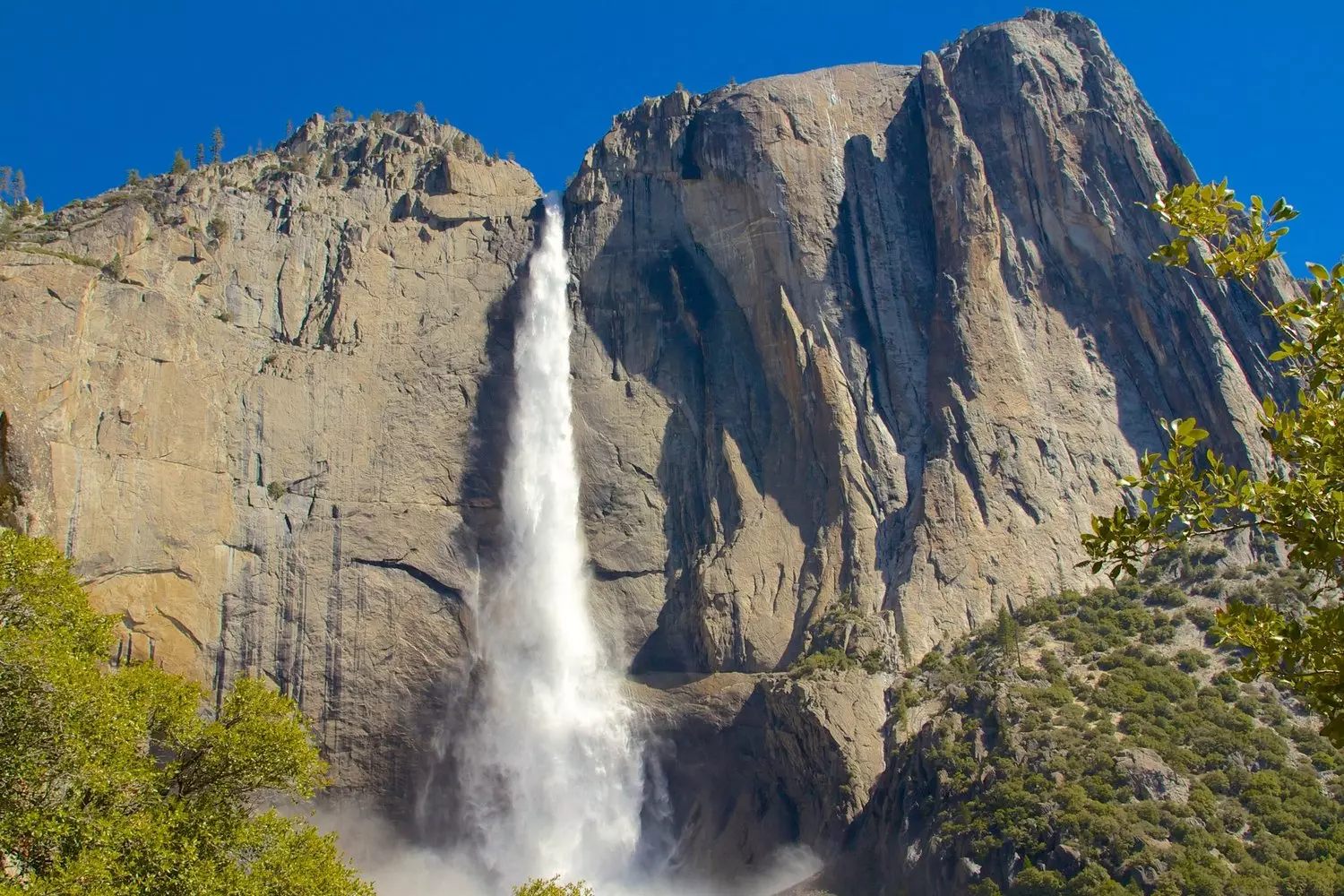 Yosemite's Powerful Waterfalls: Nature's Spectacular Show Majestic waterfall cascading down granite cliffs in Yosemite National Park surrounded by lush greenery under blue skies
