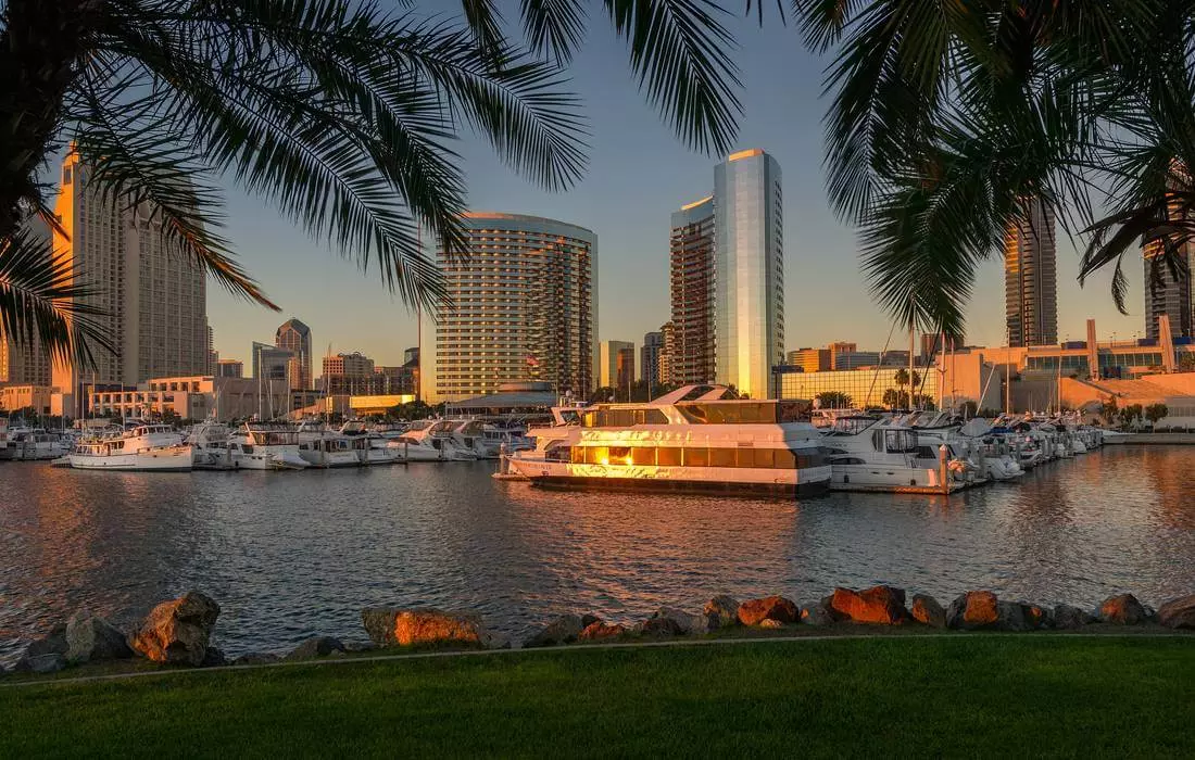 San Diego Waterfront — Vibrant Harbor Views & Maritime Charm A scenic view of San Diego's waterfront, featuring sailboats docked in the harbor, the iconic Embarcadero promenade, and the historic Maritime Museum with its collection of ships, including the Star of India, under a sunny California sky