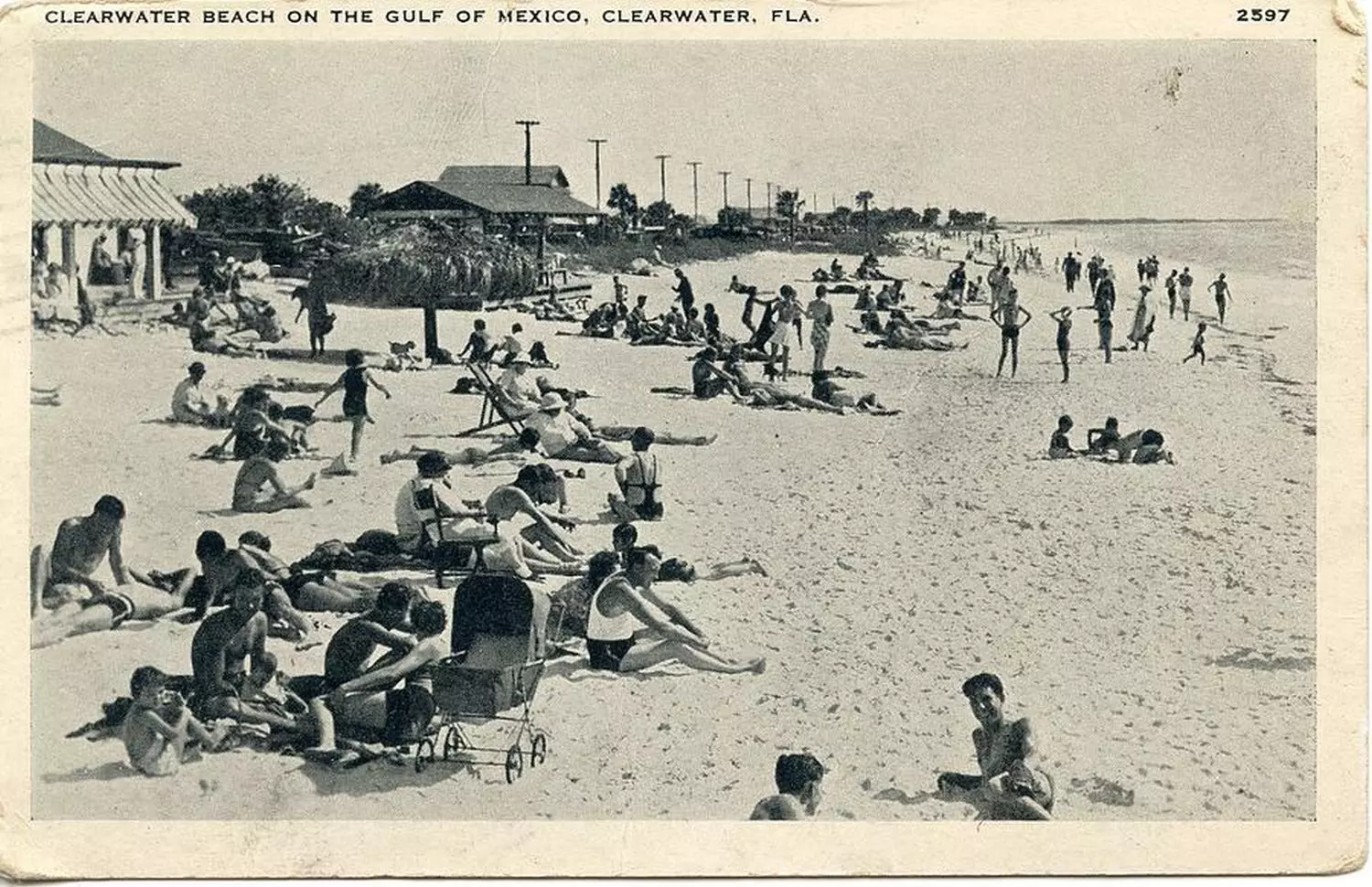 Clearwater Beach in Retro Style: How the Resort Looked in the Last Century Antique sepia-toned photograph of Clearwater Beach (1920s-1950s) — capturing the wooden pier, early beach cottages, vintage automobiles along the shore, and swimmers in period swimwear
