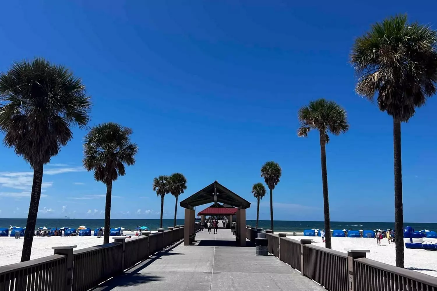 Iconic Clearwater Beach Pier: Florida's Premier Waterfront Destination Wooden Clearwater Beach Pier extending into turquoise Gulf of Mexico waters. Fishermen with rods and strolling tourists visible along the sides
