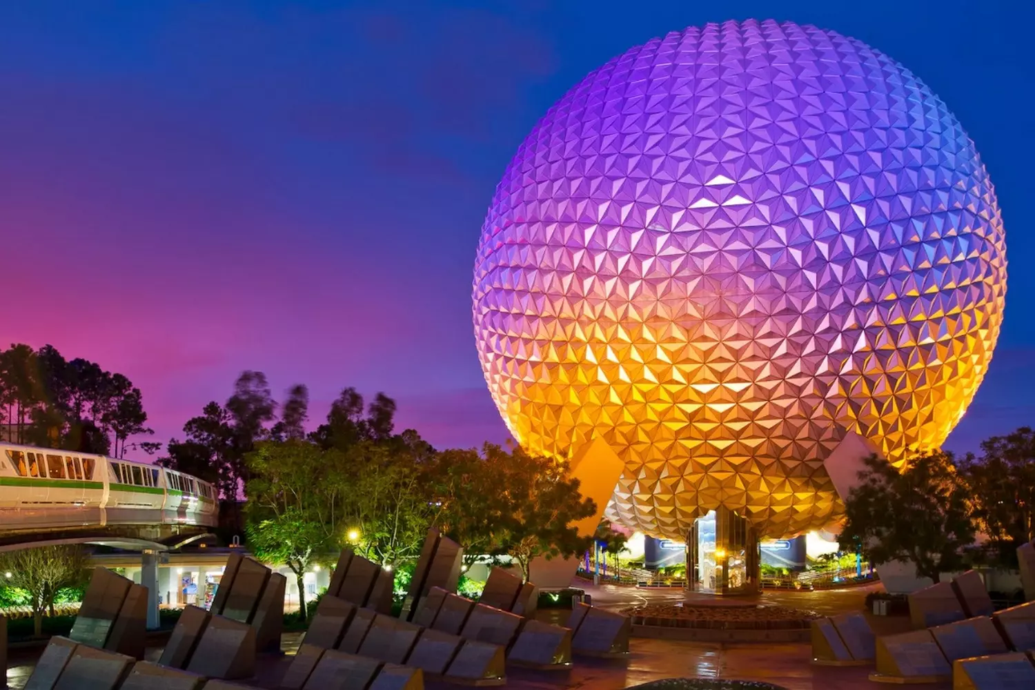 Evening view of Epcot — the iconic Spaceship Earth illuminated Epcot's Spaceship Earth at night with lights and water reflection