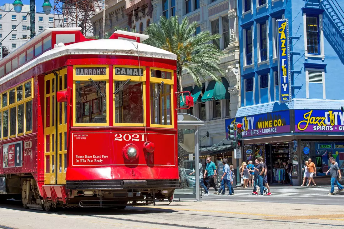 The Canal Street Car is an iconic New Orleans landmark A red streetcar on Canal Street in New Orleans next to shops and palm trees