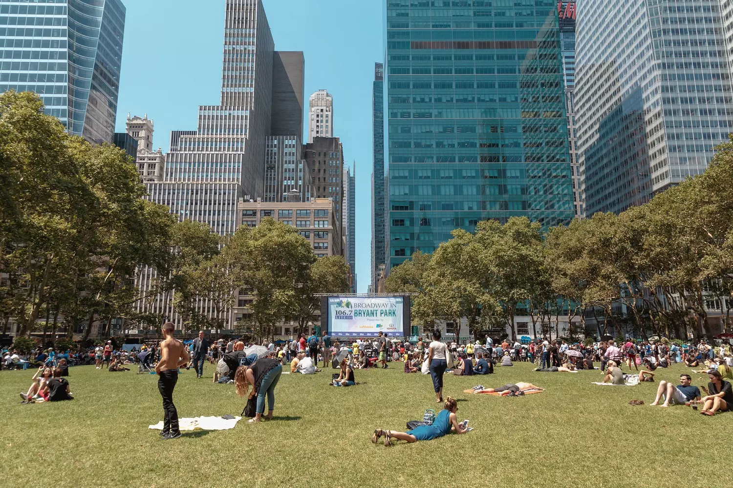 Audience members are enjoying a free Broadway show in Bryant Park Audience members are sitting on the lawn of Bryant Park during the performance