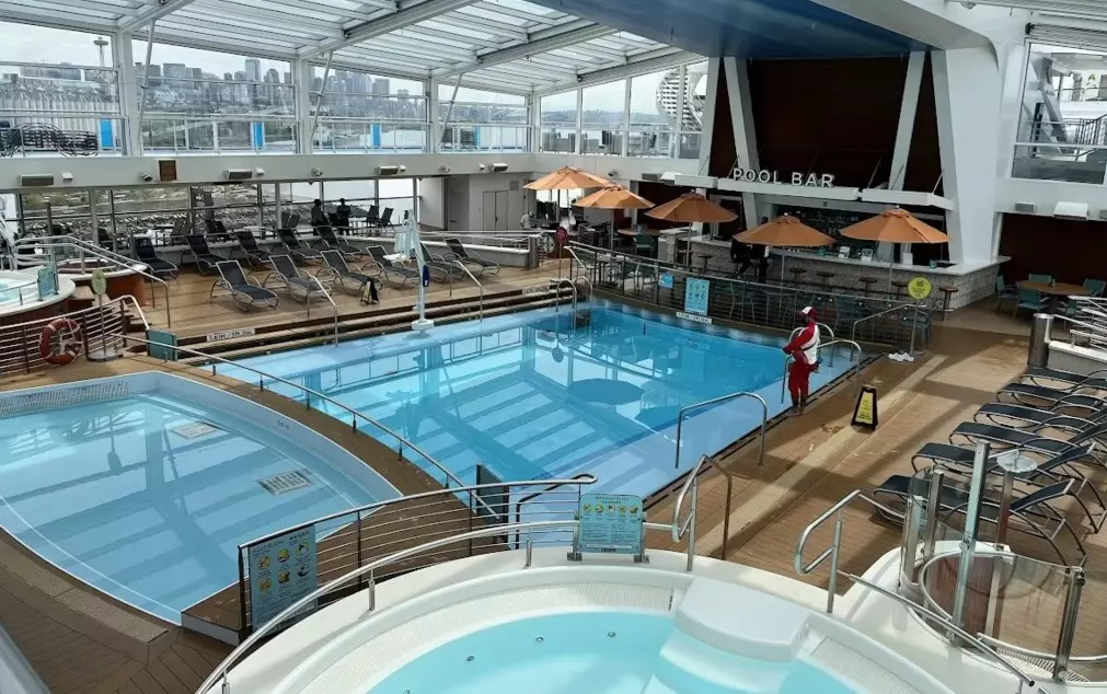 Luxury Poolside Retreat: Quantum of the Seas' Stunning Indoor Pool Area Elegant indoor pool deck aboard Royal Caribbean's Quantum of the Seas, featuring crystal-clear waters, comfortable loungers, and panoramic ocean views through massive glass windows, creating a serene oasis at sea