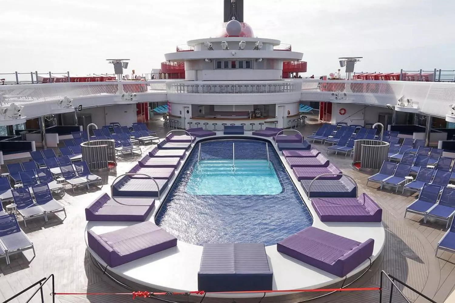 Serene Escape: Valiant Lady's Stunning Indoor Pool Oasis | Virgin Voyages Indoor pool area on Valiant Lady cruise ship with modern design, comfortable loungers and relaxing ambiance