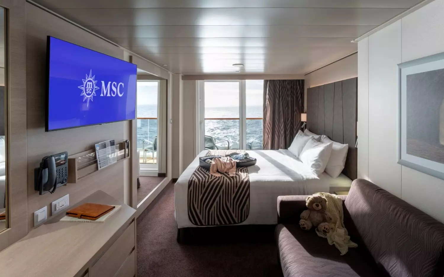 Elegant Stateroom Experience Aboard MSC World America Cruise Ship Luxurious modern cabin on MSC World America cruise ship with comfortable bed, elegant decor and ocean view