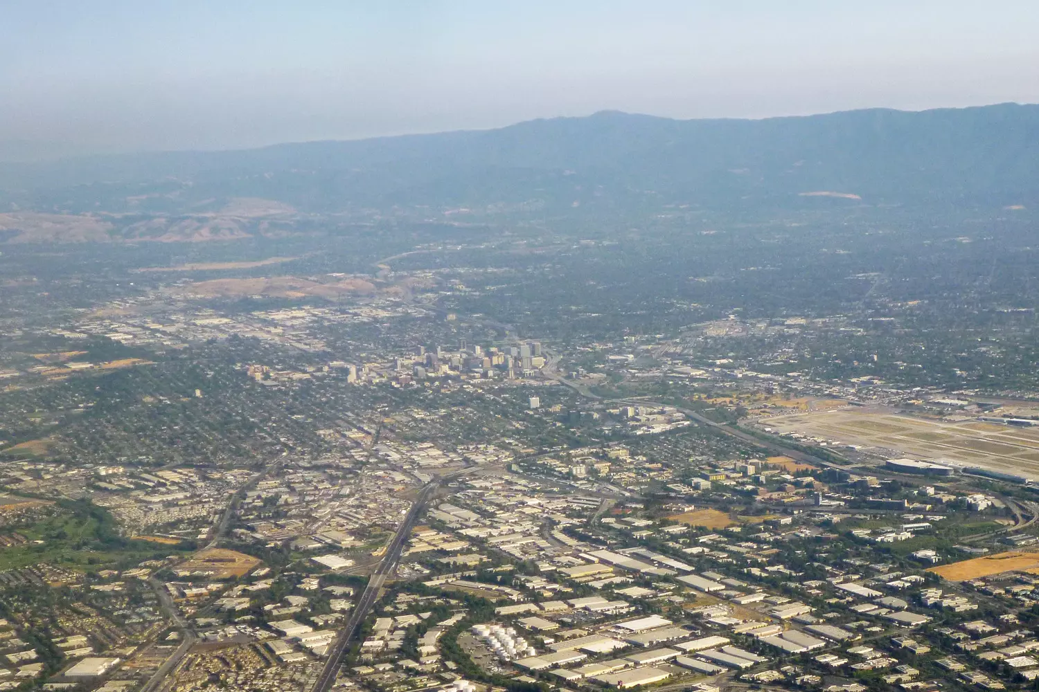Silicon Valley from above — the heart of global tech innovation Aerial view of Silicon Valley with office buildings, greenery, and mountains in the background