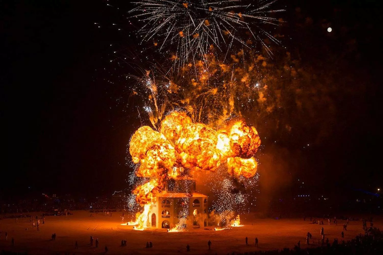 Костер на Burning Man: Магия огня под пустынным небом Огромный костер освещает ночь на фестивале Burning Man, окруженный завороженной толпой в пустыне