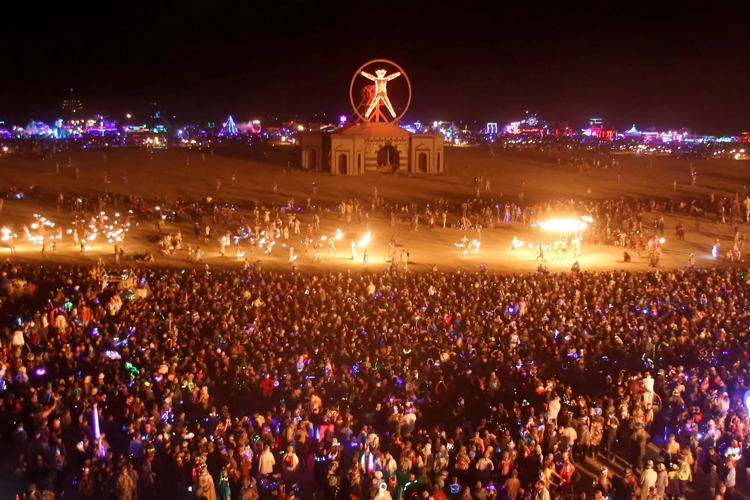 Ночной Burning Man: Пустыня, музыка и бесконечная энергия Энергичная ночная вечеринка на фестивале Burning Man: неоновые огни, танцующая толпа и яркие арт-объекты под звёздным небом пустыни