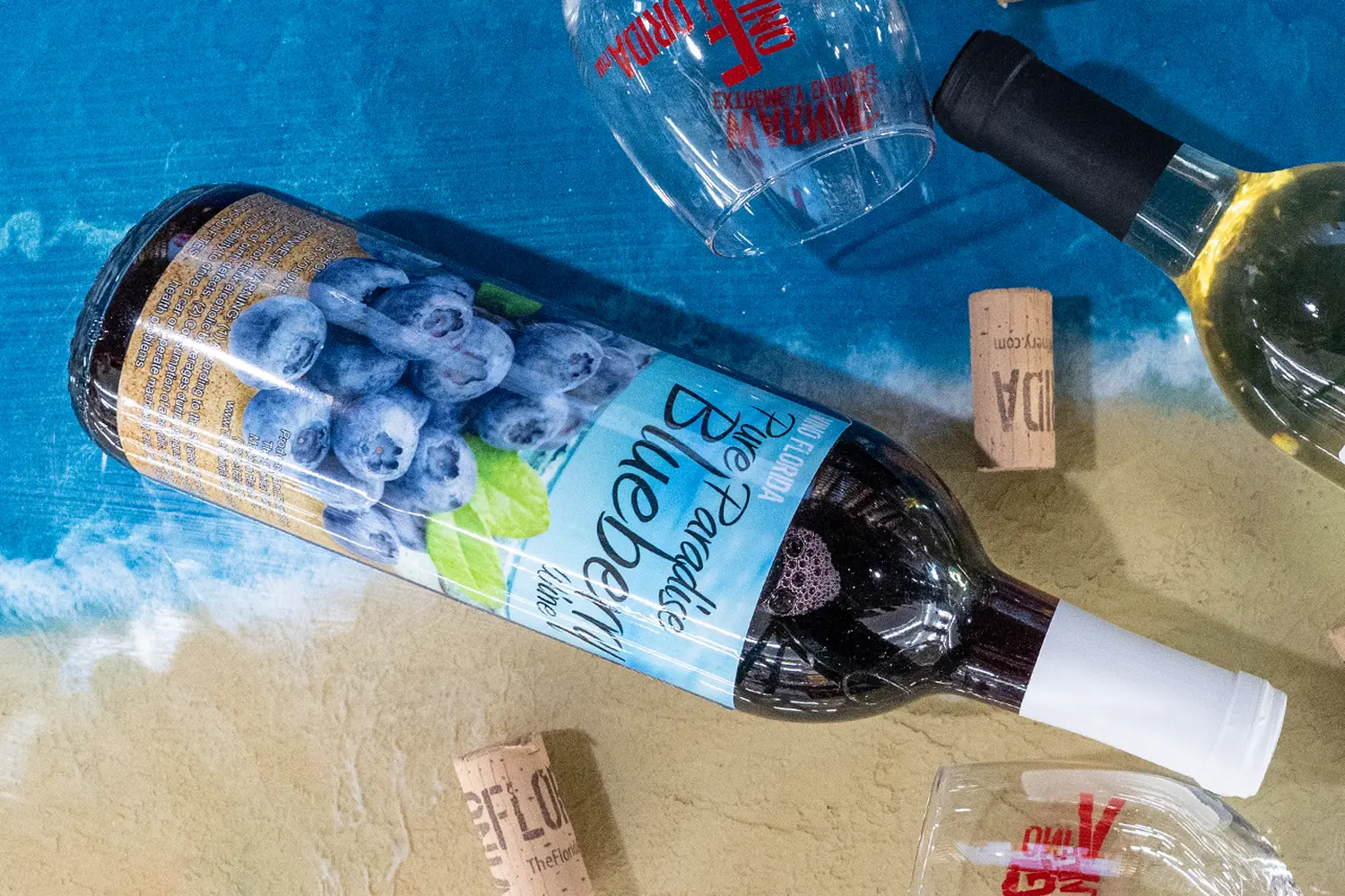 Florida's Sweet Secret: Sunshine in a Bottle of Berry Wine A bottle of vibrant Florida berry wine with juicy strawberries and blueberries surrounding it on a tropical-style wooden table, capturing the essence of local fruit flavors