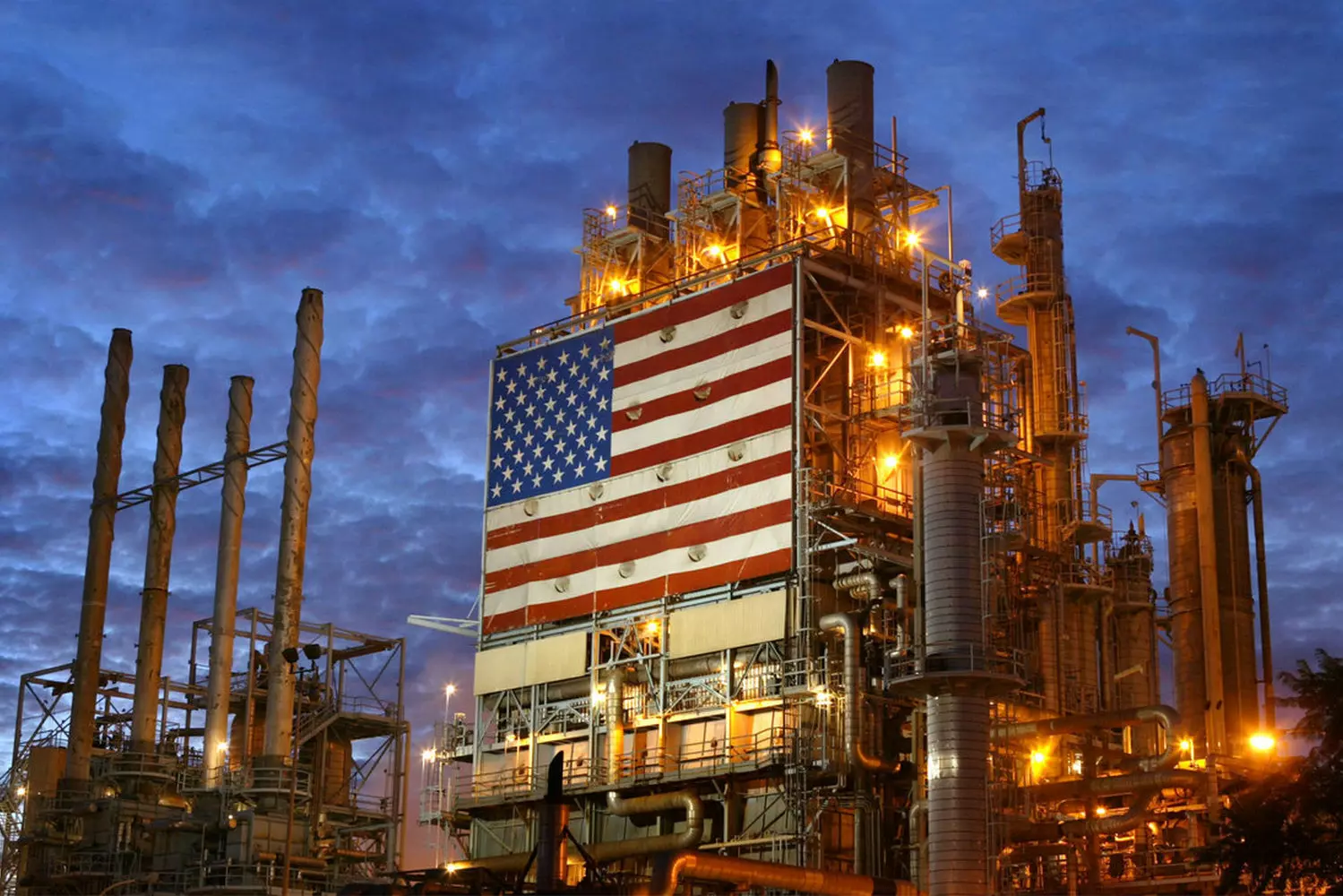Oil Refinery in the USA: Powering the Nation’s Energy Needs A large oil refinery in the USA with smokestacks, pipelines, and storage tanks under a cloudy sky, showcasing the country's industrial energy production