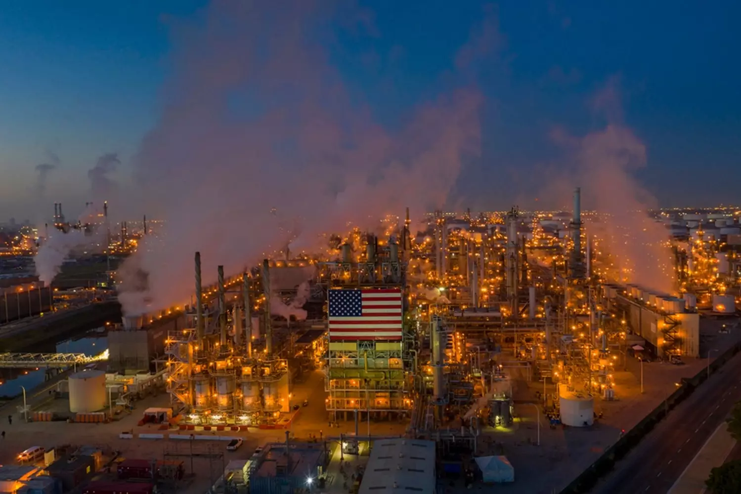 Industrial Smog Over US Oil Refinery: The Environmental Cost of Energy Production Thick smoke and smog billowing from an American oil refinery's smokestacks, highlighting the environmental impact of fossil fuel processing