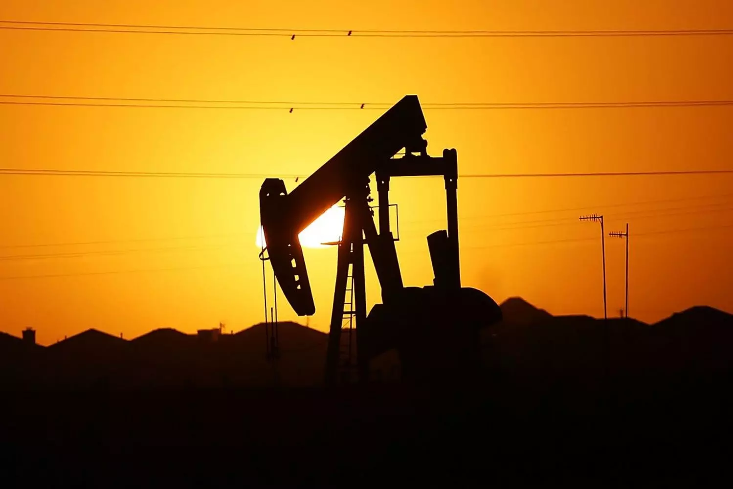 Oil Production in the USA: Powering the Nation's Energy Independence A modern oil drilling rig in operation at an American oil field, with workers and heavy equipment extracting crude oil under a clear blue sky