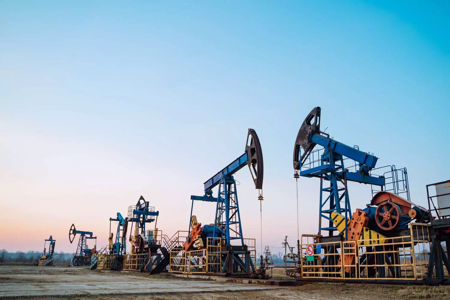 Oil Production in the USA: Powering the Nation's Energy Independence A modern oil drilling rig in operation at an American oil field, with workers and heavy equipment extracting crude oil under a clear blue sky