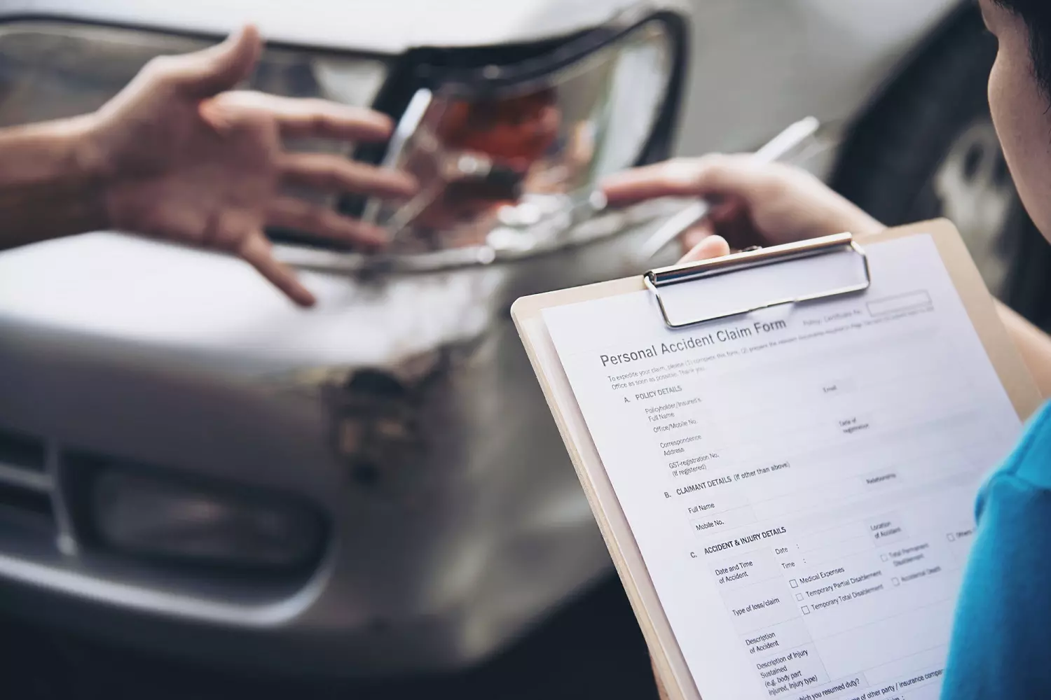 Filling out an insurance claim form after a car accident A person is filling out an insurance claim form after an accident