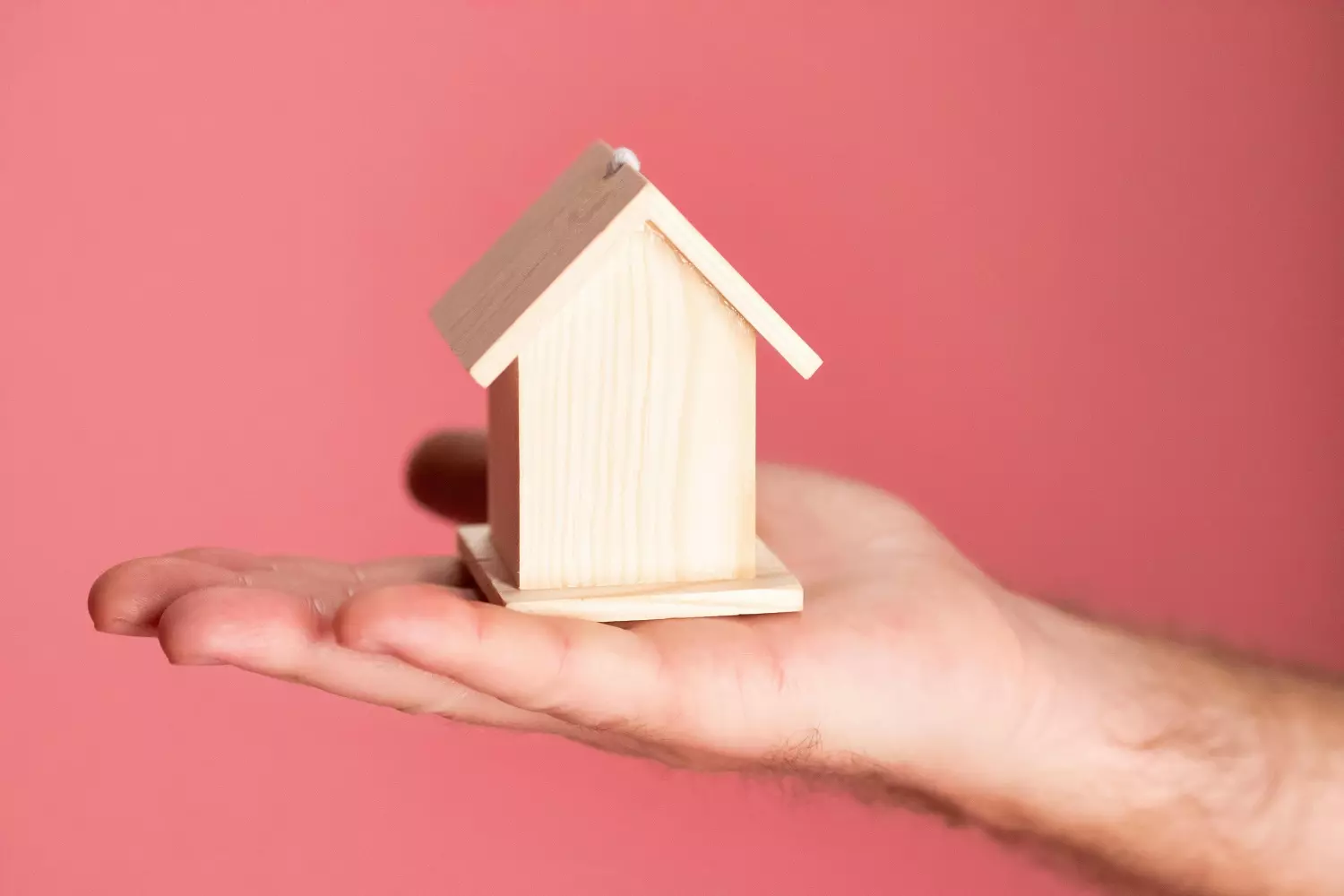 Real estate management — a toy house in hand A person holding a wooden house in their hand