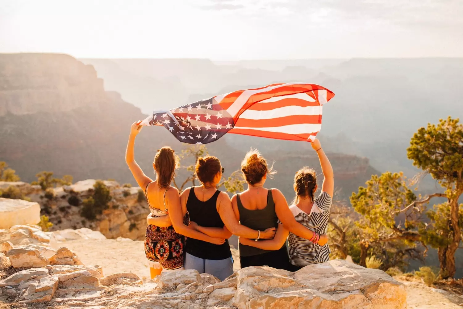 What are the types of US visas — inspiring landscapes and the American spirit What are the types of American visas — a group of girls with the US flag against the backdrop of a breathtaking canyon