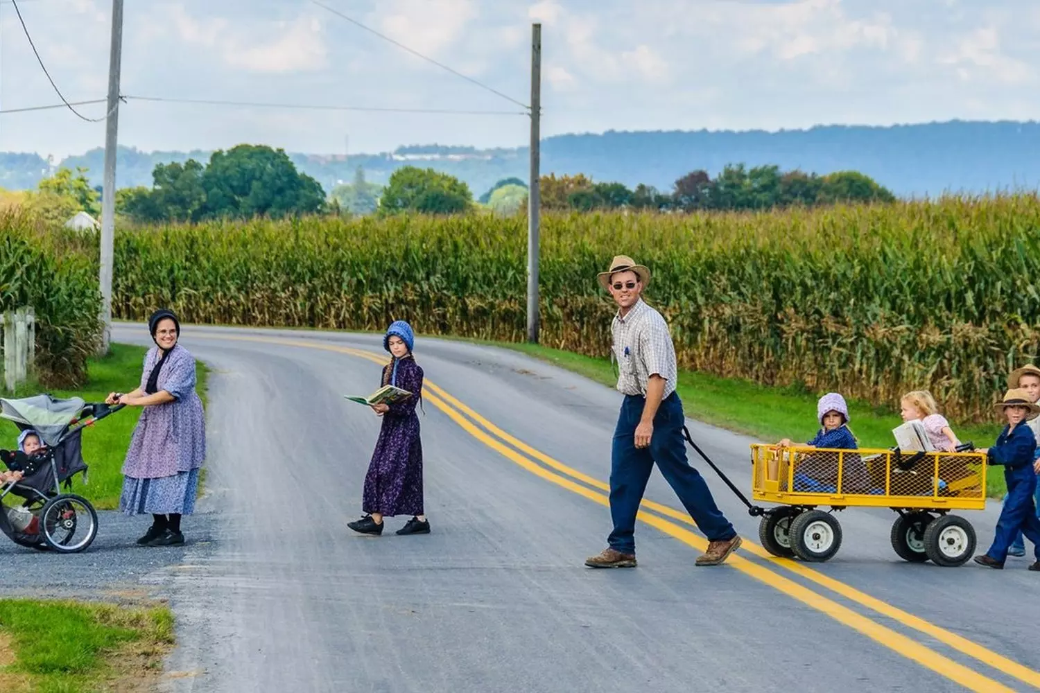 Traditional Amish family walking across a country road Amish family crossing a rural road in traditional clothing