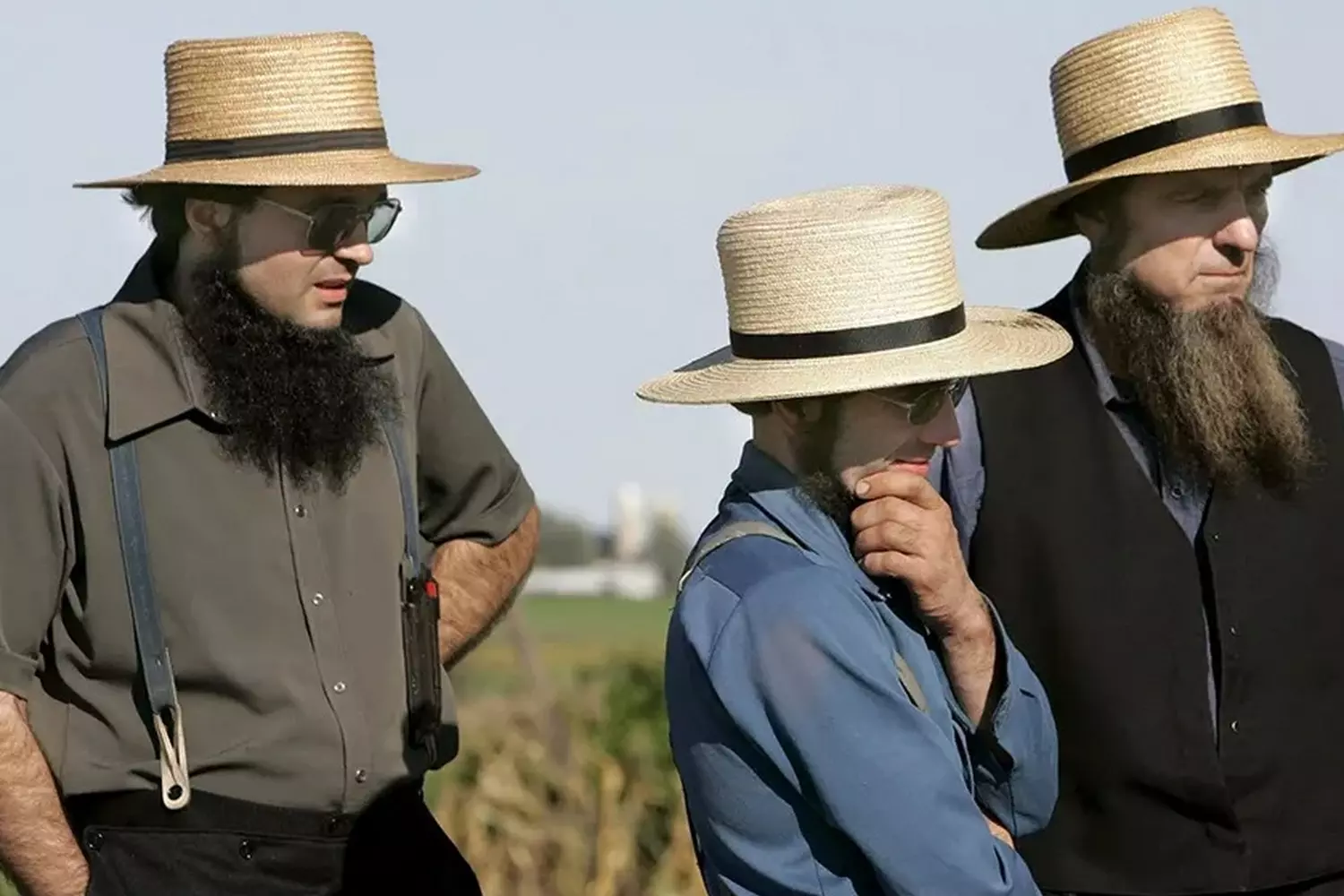 Amish men dressed in plain clothes and wide-brimmed hats Group of Amish men in traditional clothing with hats and beards