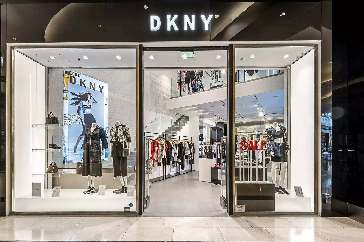 Магазин DKNY: Нью-Йоркский стиль в каждом образе Фото современного бутика DKNY с фирменным черным оформлением и витринами, демонстрирующими городские образы и кожаные куртки