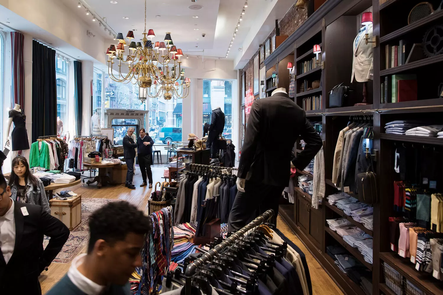 Магазин Brooks Brothers: Два века безупречного стиля Фото элегантного бутика Brooks Brothers с витринами, демонстрирующими классические костюмы, рубашки и фирменный логотип Golden Fleece