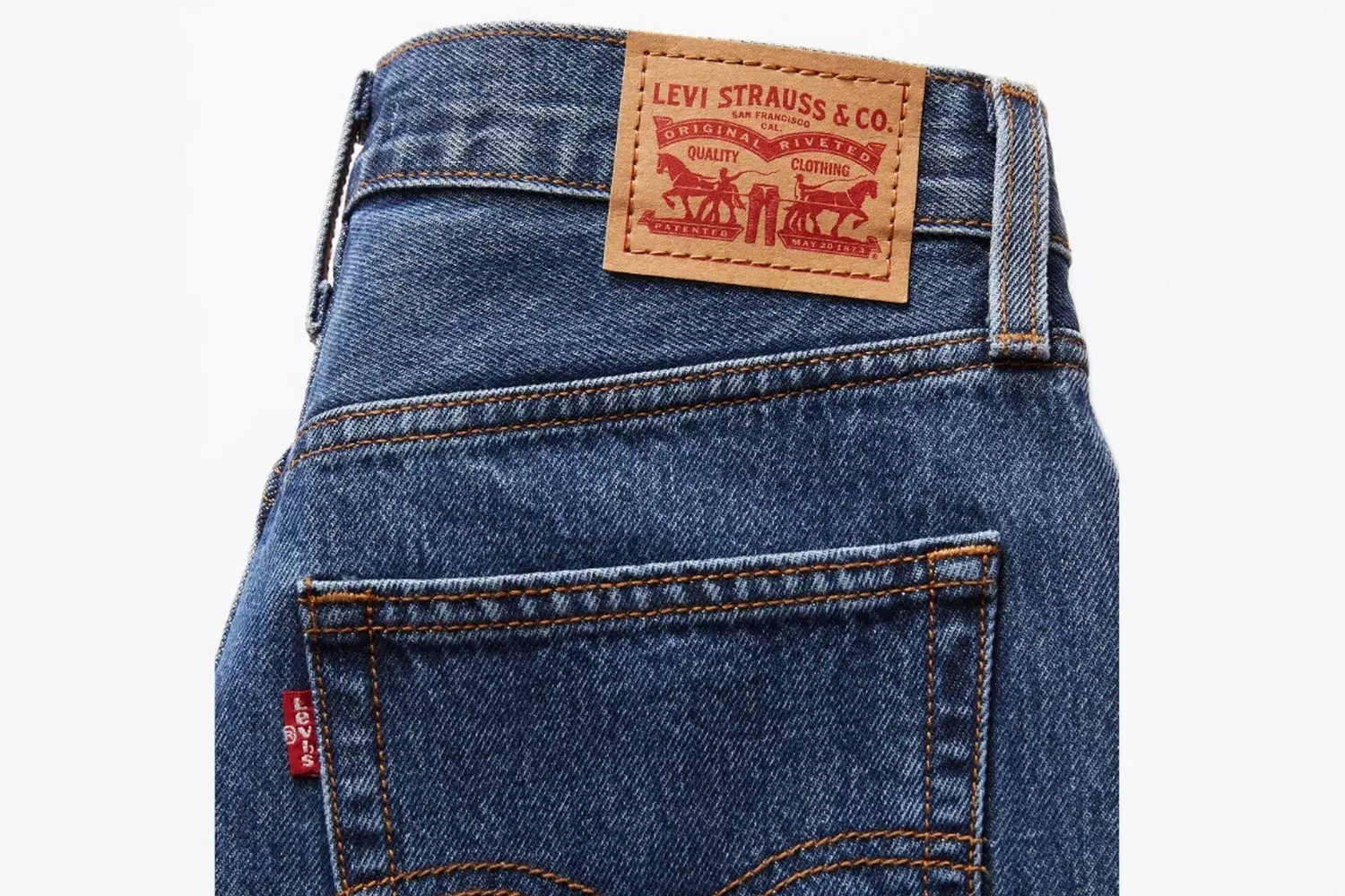 Легендарные джинсы Levi's®: Деним на все времена Классические синие джинсы Levi's®, лежащие на поверхности, с узнаваемой красной биркой и фирменной строчкой
