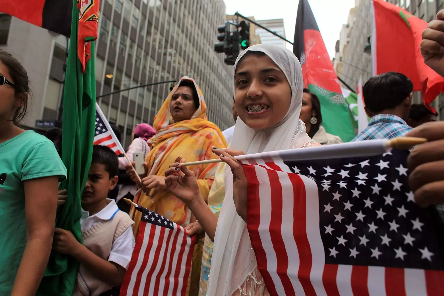 New Americans: Immigrants with U.S. Flags A diverse group of migrants at a naturalization ceremony holding small American flags, symbolizing their new citizenship status