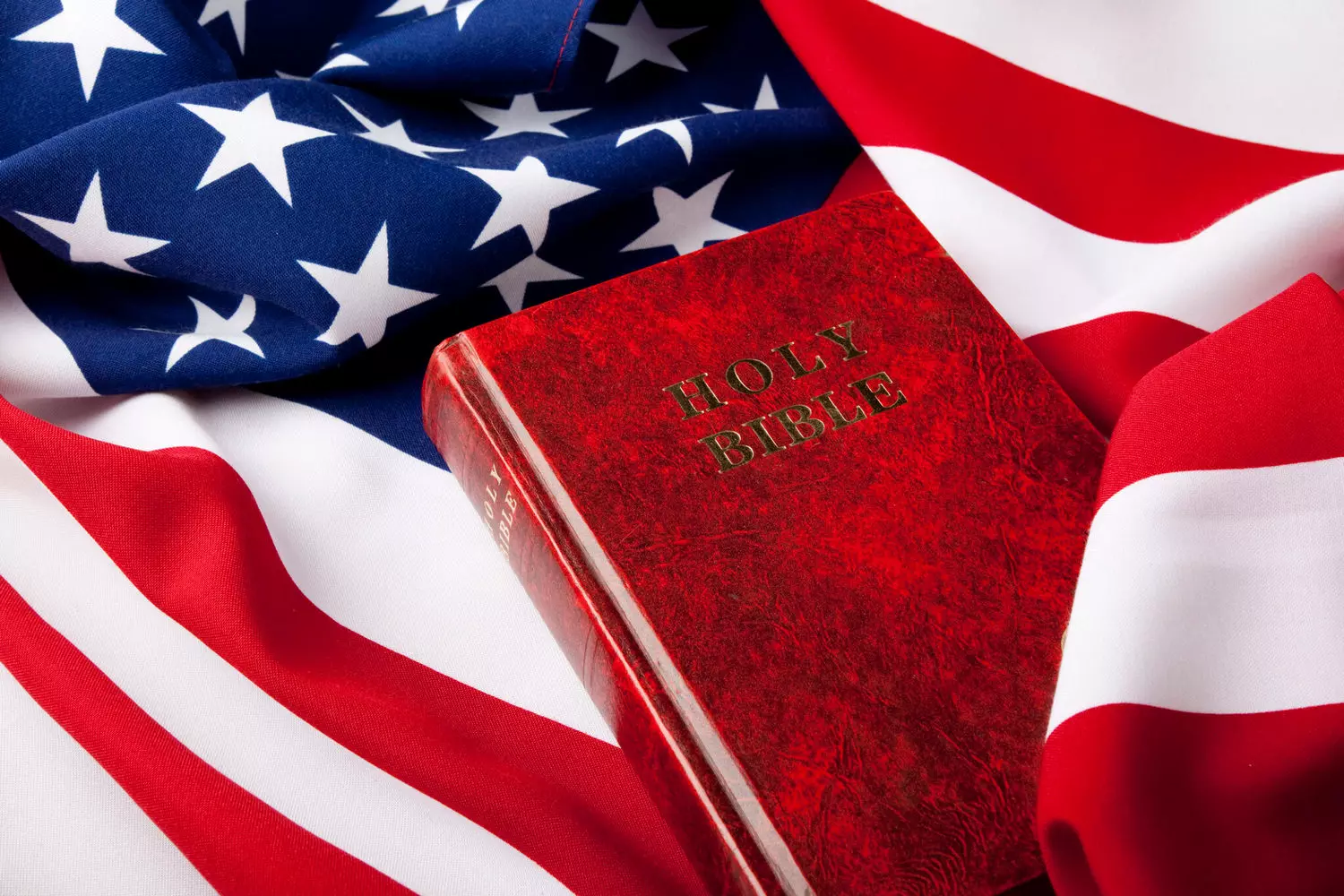 The Bible and the Stars and Stripes: Faith and Patriotism in American Life An open Bible against the backdrop of a waving American flag — a symbol of the unity between Christian faith and the national identity of the United States