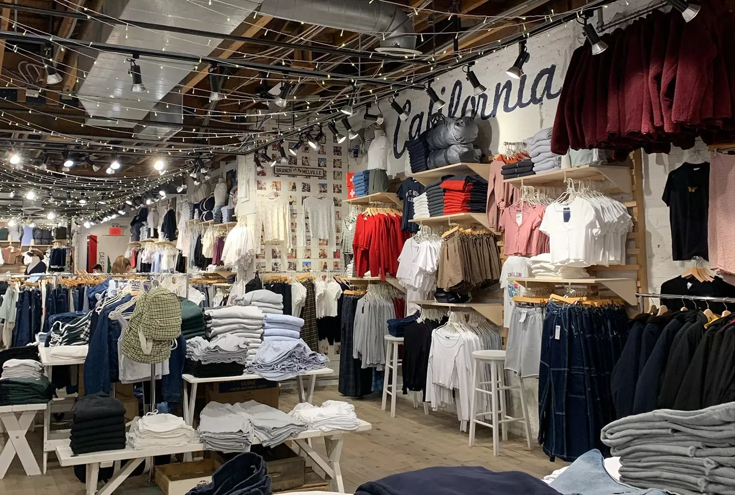 One size fits all? Well, almost The interior of the Brandy Melville store in pastel tones with surf decor: stacked tops, floral skirts, and 'one size' jeans on wooden shelves