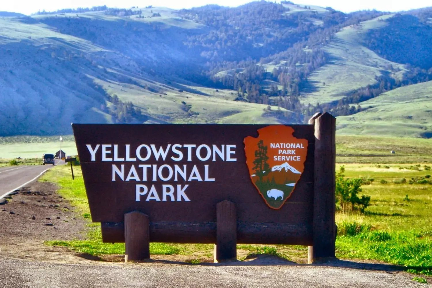Iconic Yellowstone National Park Welcome Sign — Gateway to America’s Wilderness Wooden Yellowstone National Park entrance sign with carved letters against a backdrop of pine trees and mountains