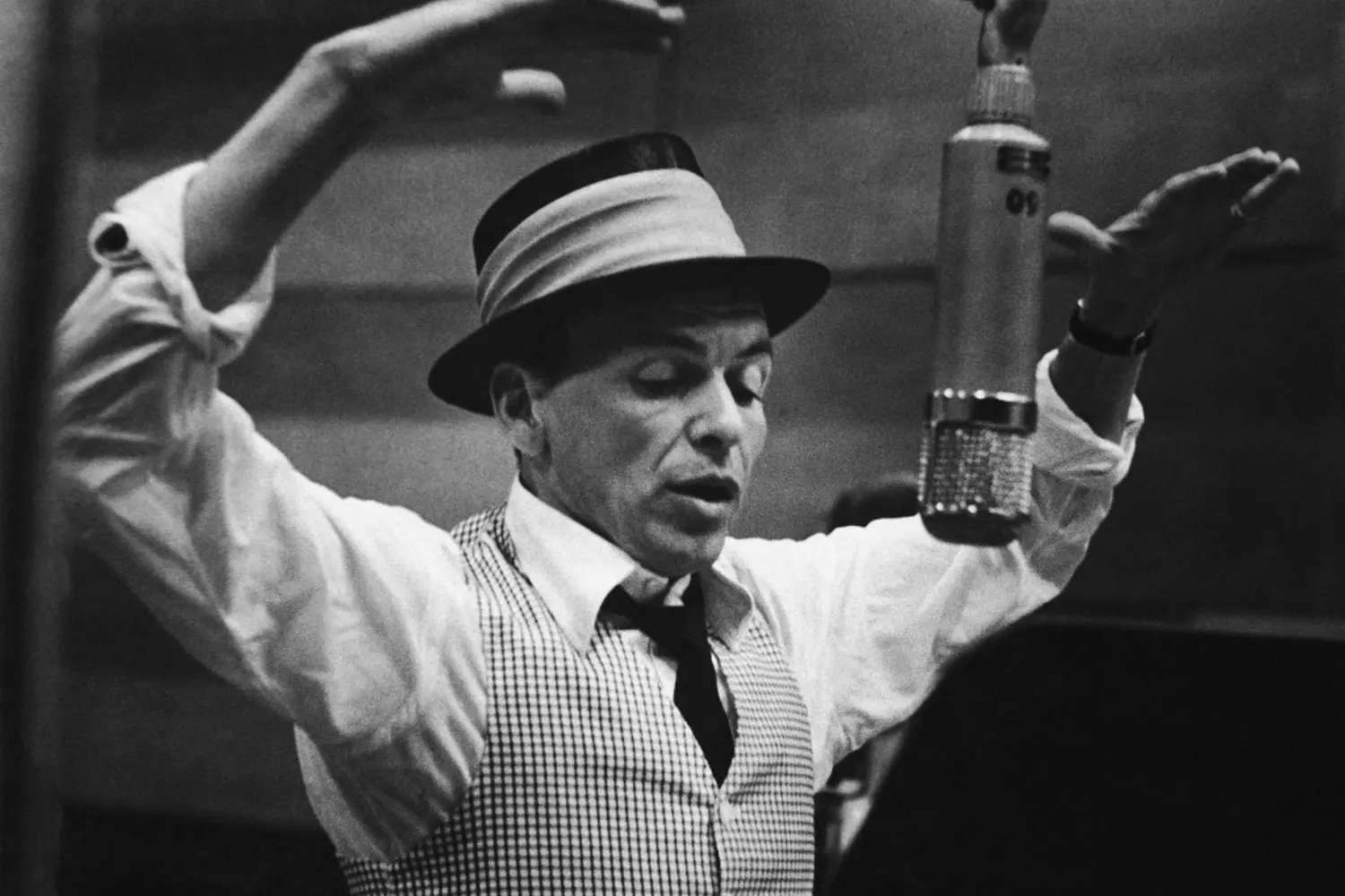 Frank Sinatra’s style as the epitome of elegance and confidence Frank Sinatra in his signature hat and suit, singing into a microphone