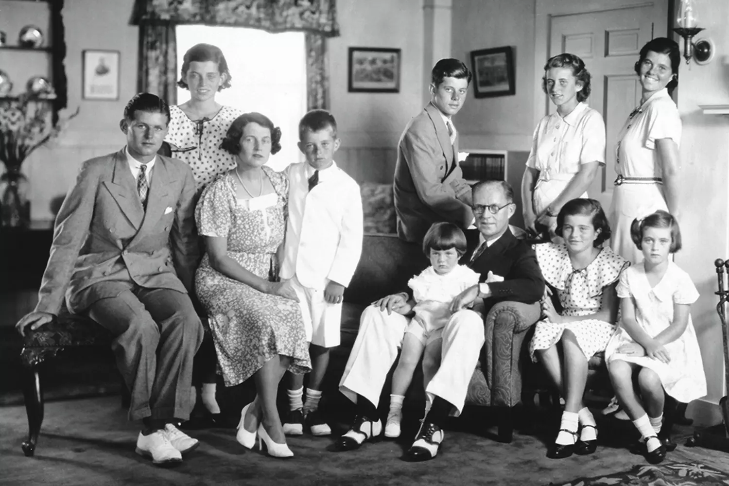 Little Kennedy with His Family: A Rare Childhood Photo of the Future President A black-and-white photo of John F. Kennedy at around 6 years old with his parents, Joseph and Rose Kennedy, and his siblings at their home in Brookline, Massachusetts
