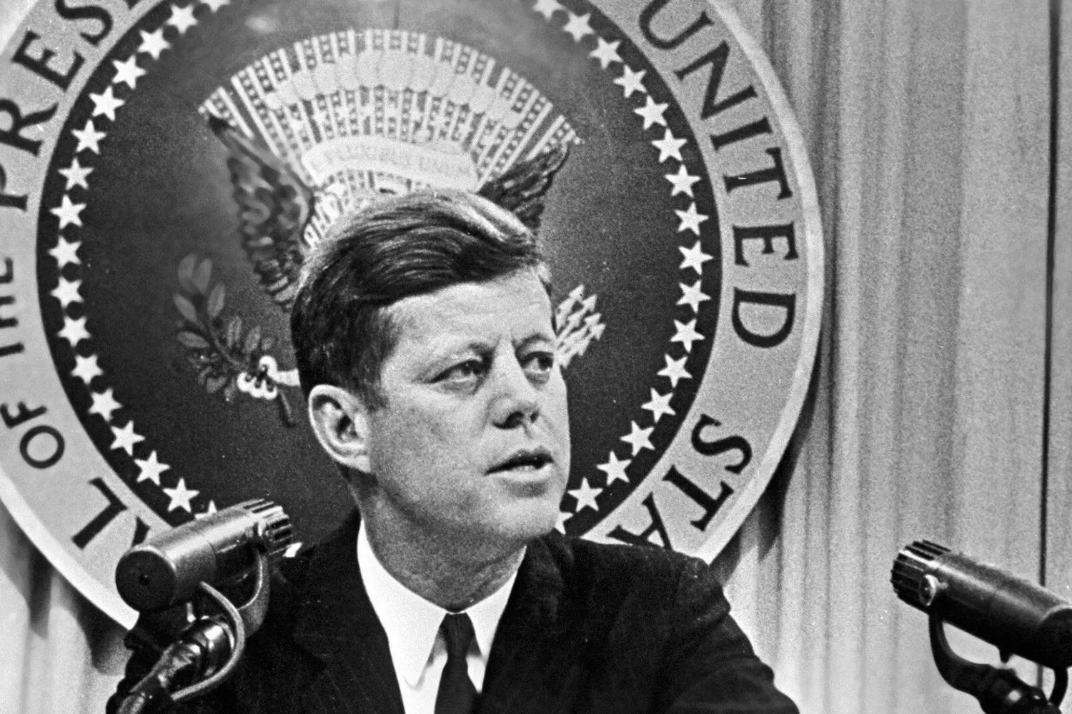 JFK Mid-Speech: Capturing the Fire of Kennedy's Oratory President John F. Kennedy in the heat of a passionate address, mouth open mid-sentence with hands frozen in emphatic gesture