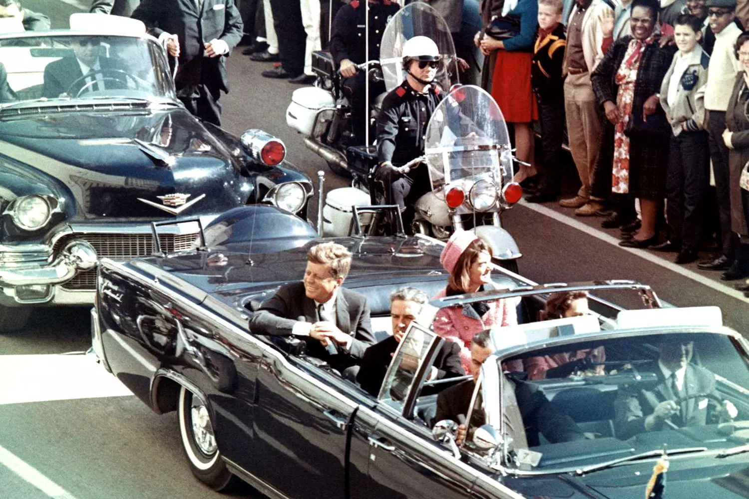 Kennedy in the Presidential Motorcade: The Fateful Convertible President John F. Kennedy in the back of an open 1961 Lincoln Continental limousine during a motorcade, greeting the crowd