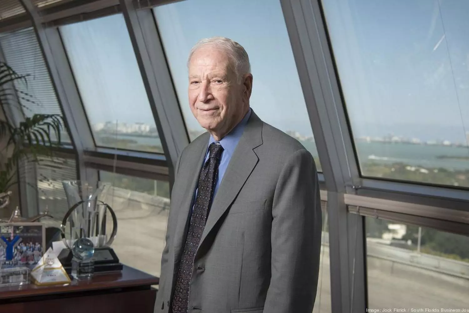 Phillip Frost – businessman and investor, photo in the office Phillip Frost in a gray suit, standing in the office with a water view