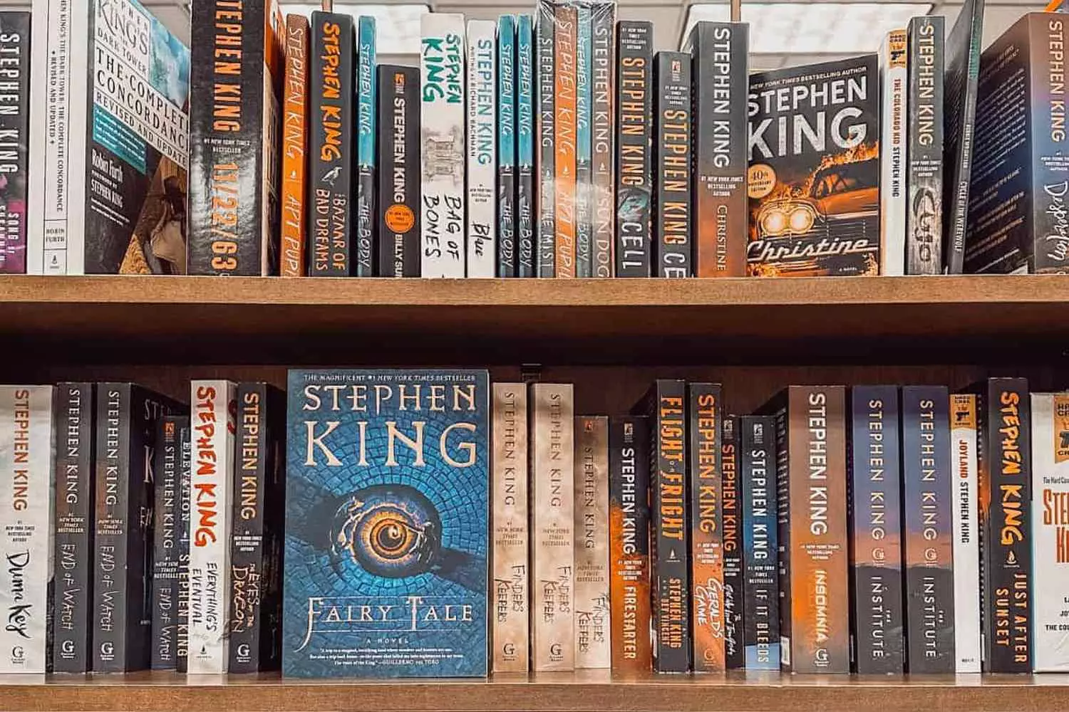 Stephen King's Literary Universe: A Shelf of Nightmares A curated collection of Stephen King's novels neatly arranged on a bookshelf, showcasing iconic titles from Carrie to The Shining and beyond