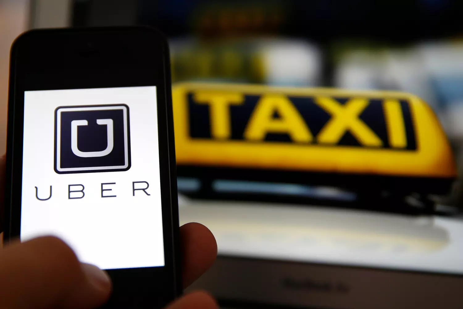 Сервис Uber для заказа такси через мобильное приложение — American Butler Мобильное приложение Uber на фоне желтого знака такси