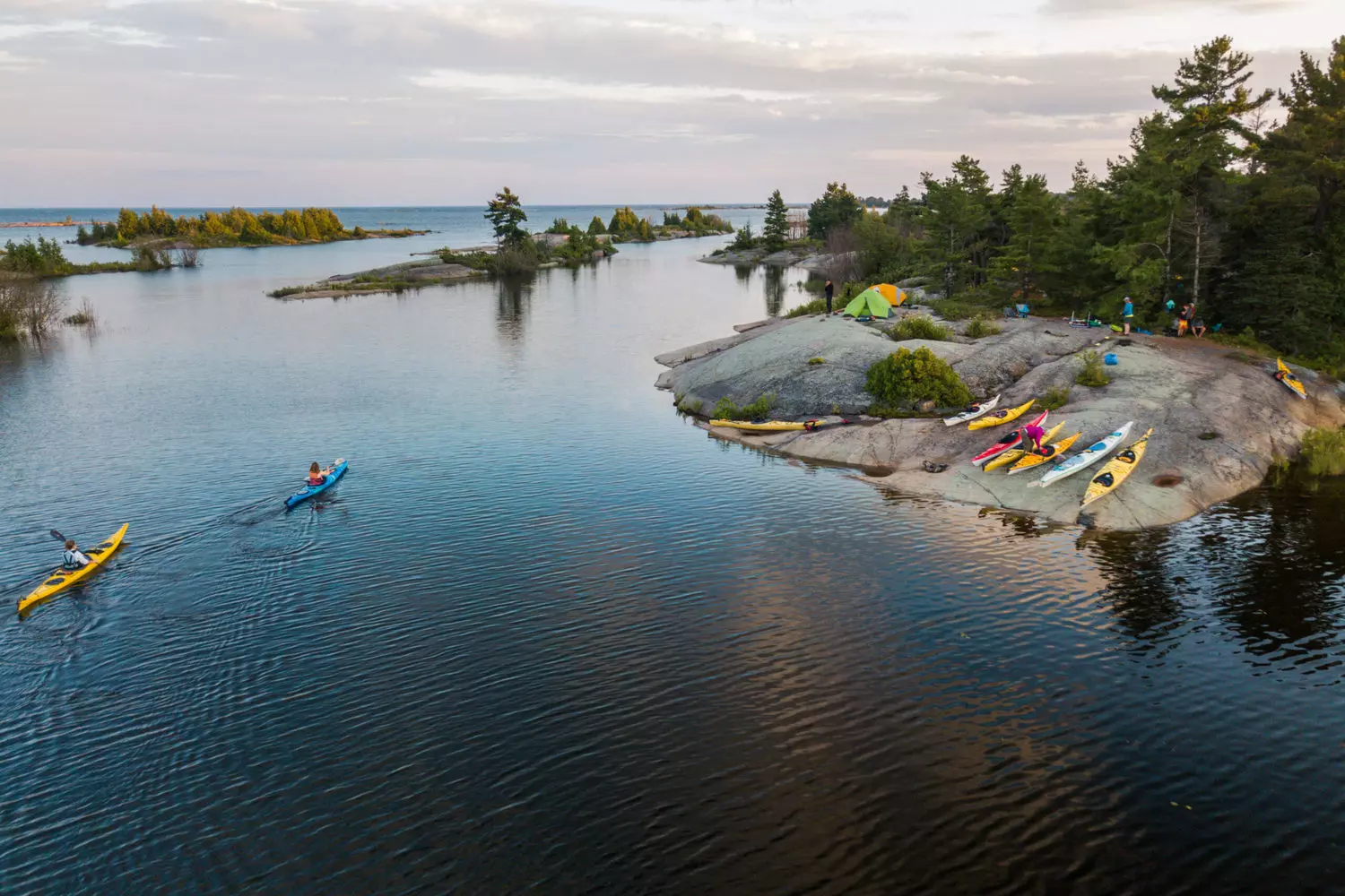 Kayaking the Great Lakes: Paddling Through Freshwater Majesty A lone kayaker glides across the crystal-clear waters of Lake Superior near Pictured Rocks, with towering sandstone cliffs reflecting in the calm surface