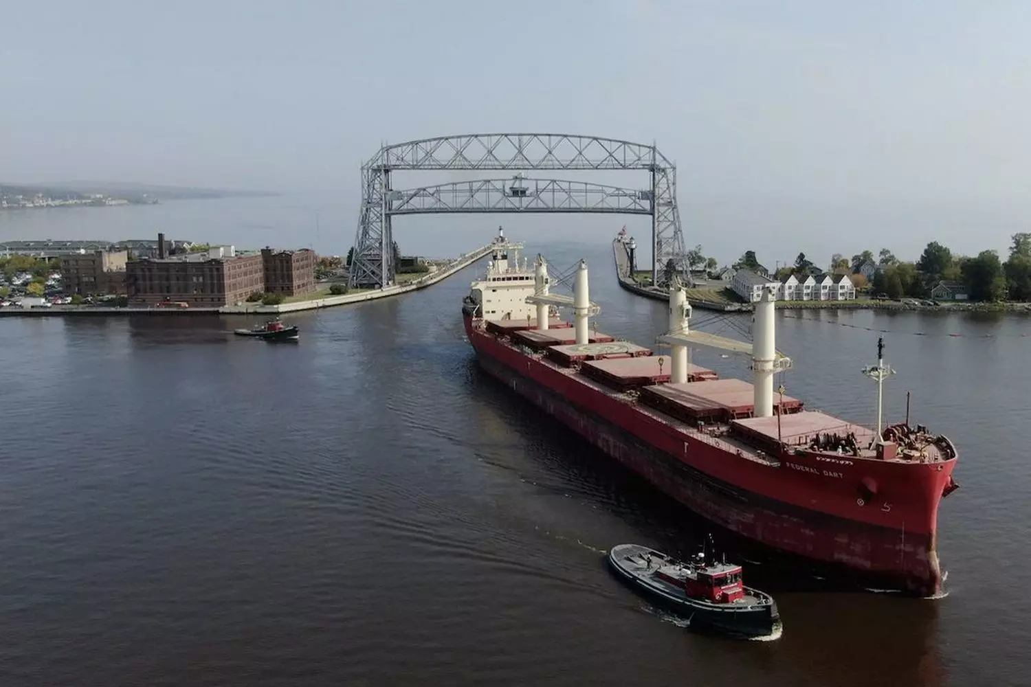Great Lakes Port: Where Industry Meets Natural Splendor Aerial view of a bustling Great Lakes industrial port with cargo ships docked alongside massive ore carriers, set against the backdrop of Lake Superior's deep blue waters